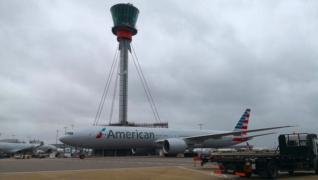 An American Airlines plane in front of an airport control tower
