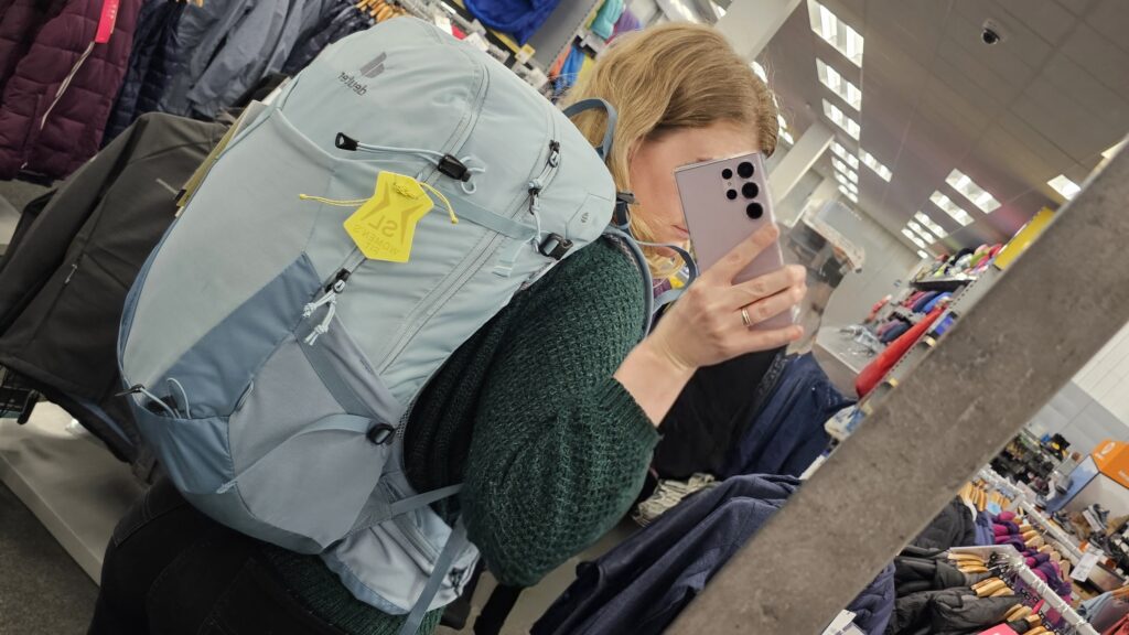 Woman trying on a light blue backpack in a shop