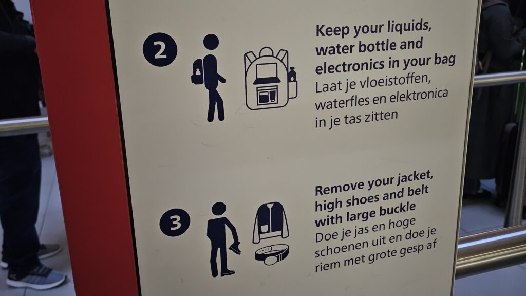 A sign showing rules for going through security at an airport. Rules include removing jacket and keeping liquids in a bag