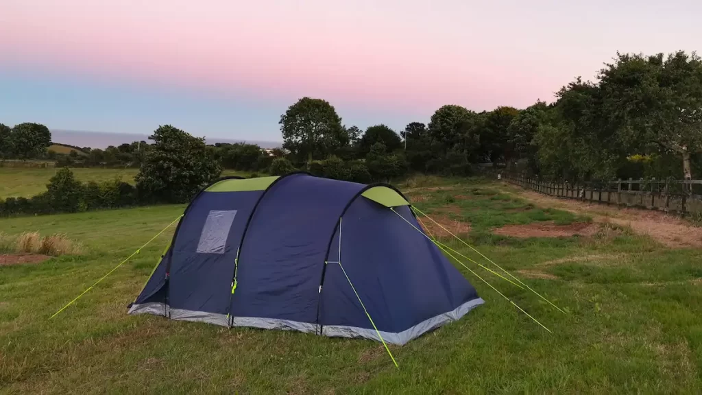 A blue tent with a pink sunset sky