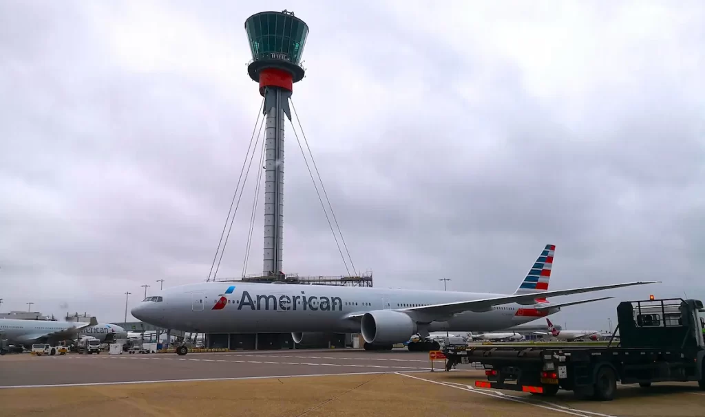 An American Airlines plane in front of an airport control tower