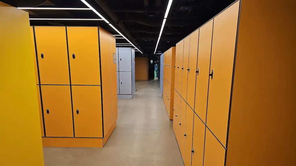 Several rows of orange storage lockers in a hostel