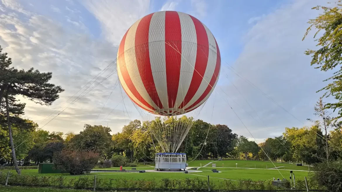 Red and white striped hot air balloon tethered in a park