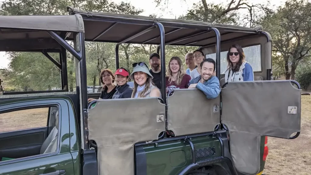 Group of young adults smiling sat in a safari jeep