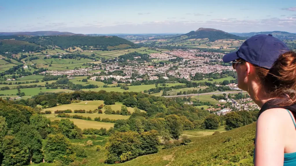 Woman on a hill looking down over a small Welsh town