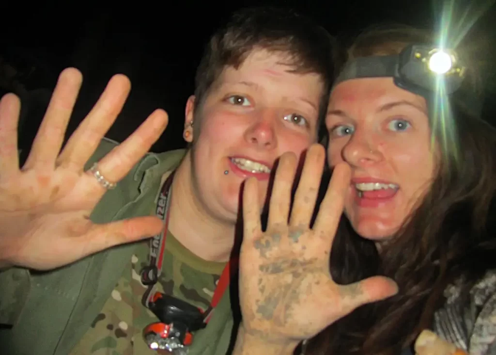 Two women volunteering in the Madagascar wilderness at night covered in mud