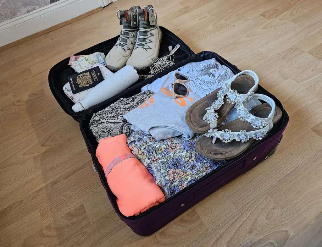An opened suitcase filled with clothes and shoes