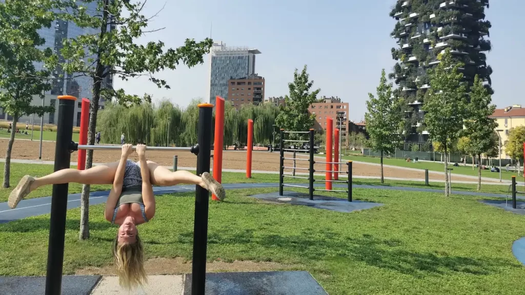 Woman upside down on a chin-up bar in a park