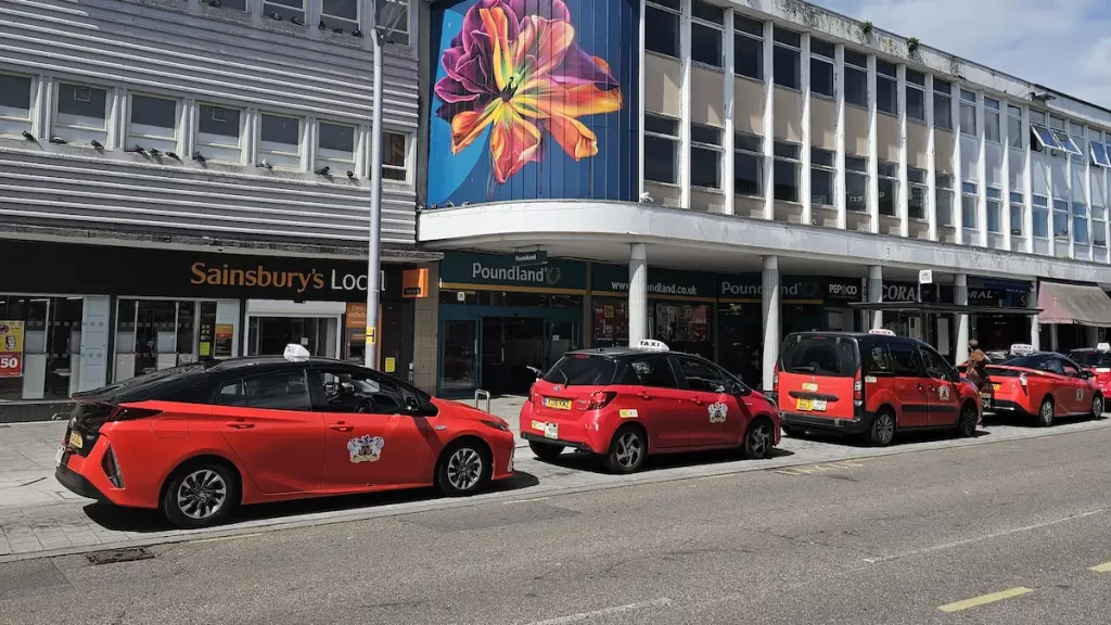 A line of red taxis outside shops in Exeter City