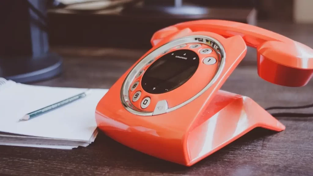 A retro orange telephone on a esk