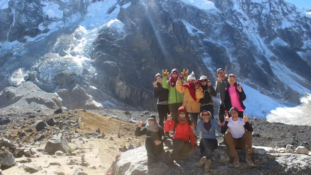 A group of young adults wearing winter clothing posing in front of a glacial mountain in Peru