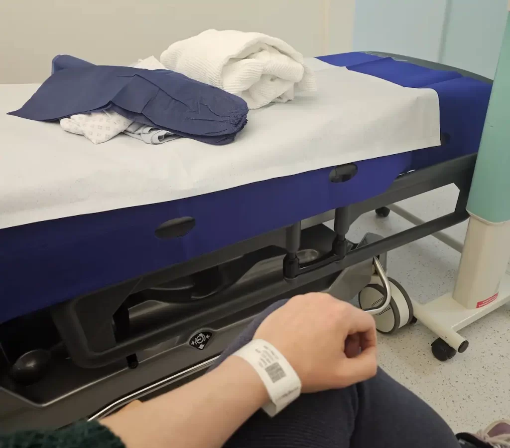 A hospital bed and close up of a medical paper wristband on a woman's wrist