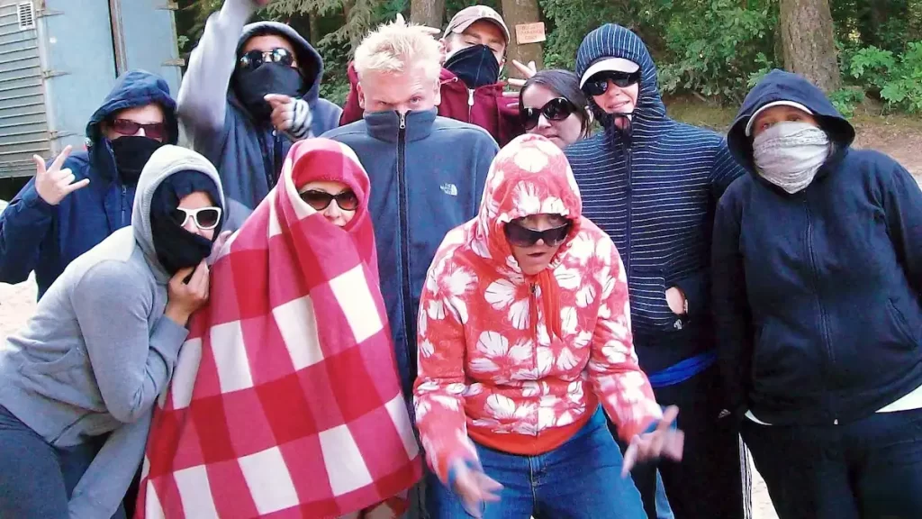 A group of young adults all wrapped up in hoodies, blankets and face masks