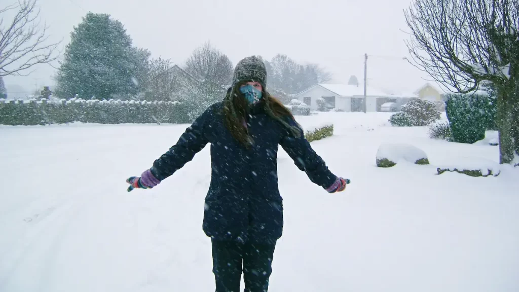 Woman wrapped up in winter clothes in the snow