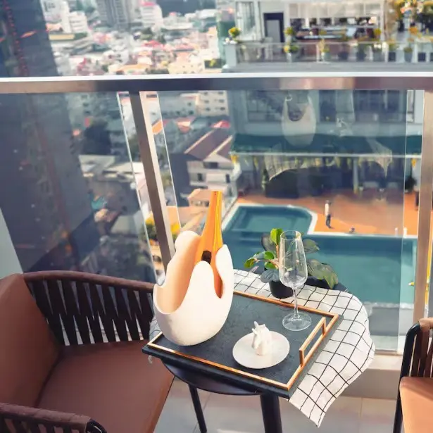 View of Phnom Penh from a skyscraper glass balcony. On the balcony is a small nicely decorated table and some chairs