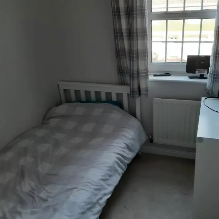 A tiny Airbnb room with a single bed and chest of drawers