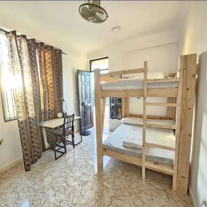 An Airbnb room with wooden bunk beds, a ceiling fan and a desk all with decorated in neutral colours