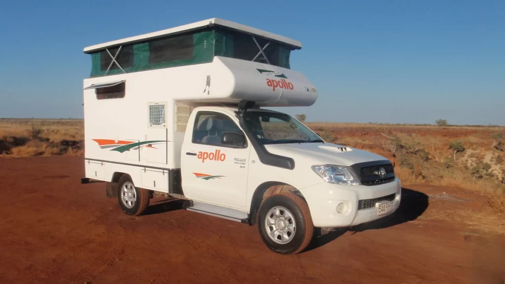 White pop-top campervan on a red dirt road