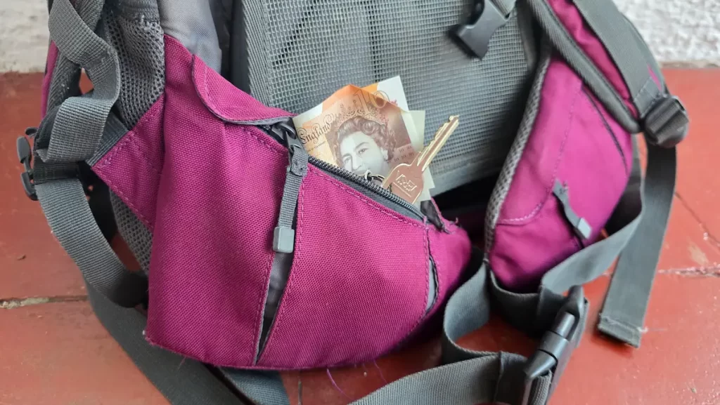 Close up of pockets on a backpack hip strap with a key and money inside