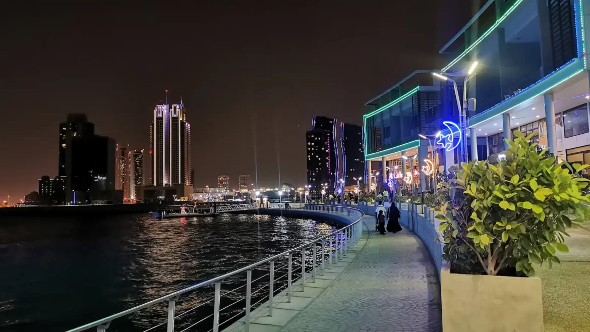 Shops and skyscrapers with neon lights lining the waterfront at night