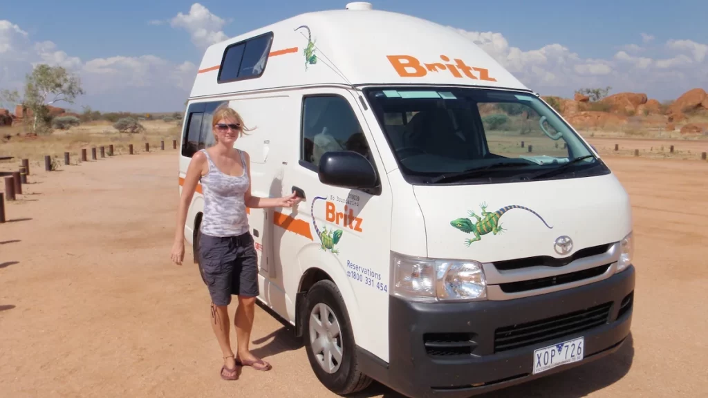 Sue, the founder of The Practical Passport, stood outside a white Britz campervan on a dusty road