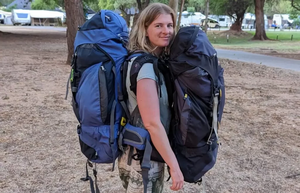 Sue carrying 2 large backpacks, one on the front of the body and one on the back