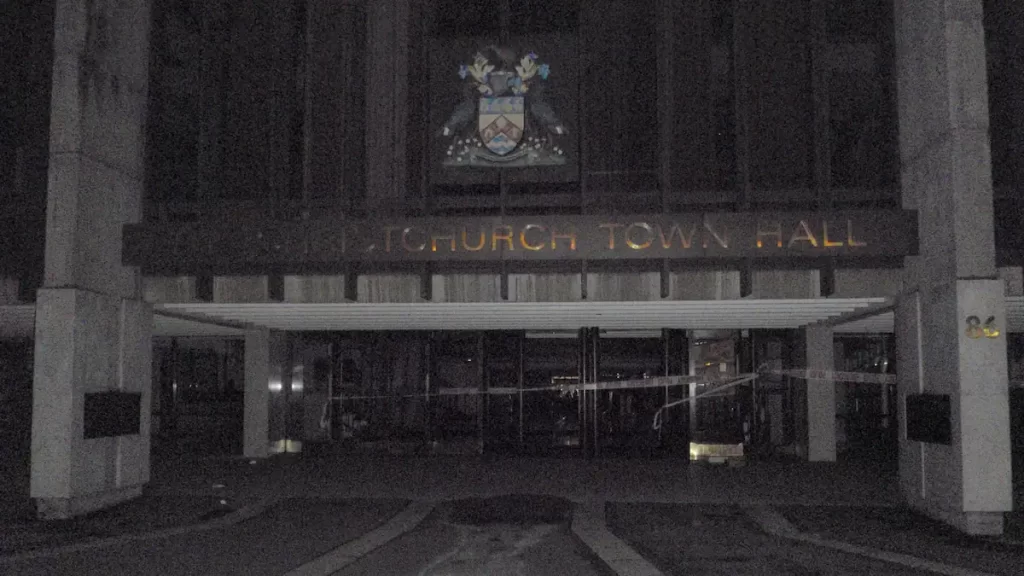 A dark and grainy image of Christchurch Town Hall in darkness and abandoned with police tape around it