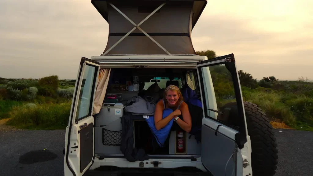 Woman lying down in the back of a pop-top campervan