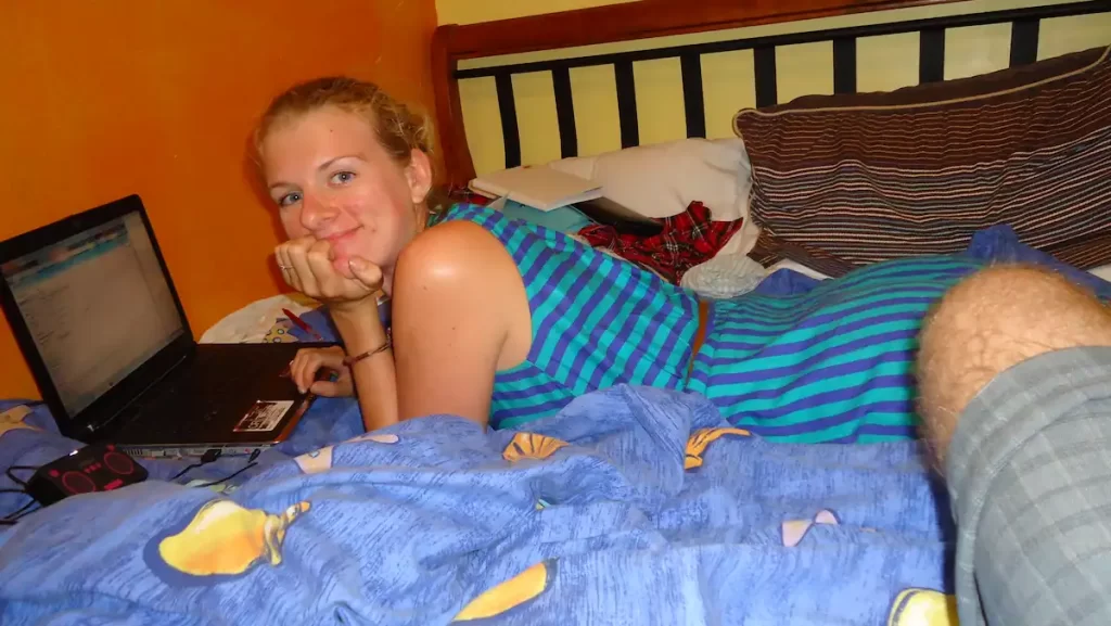 Sue lying on a bed researching on a laptop