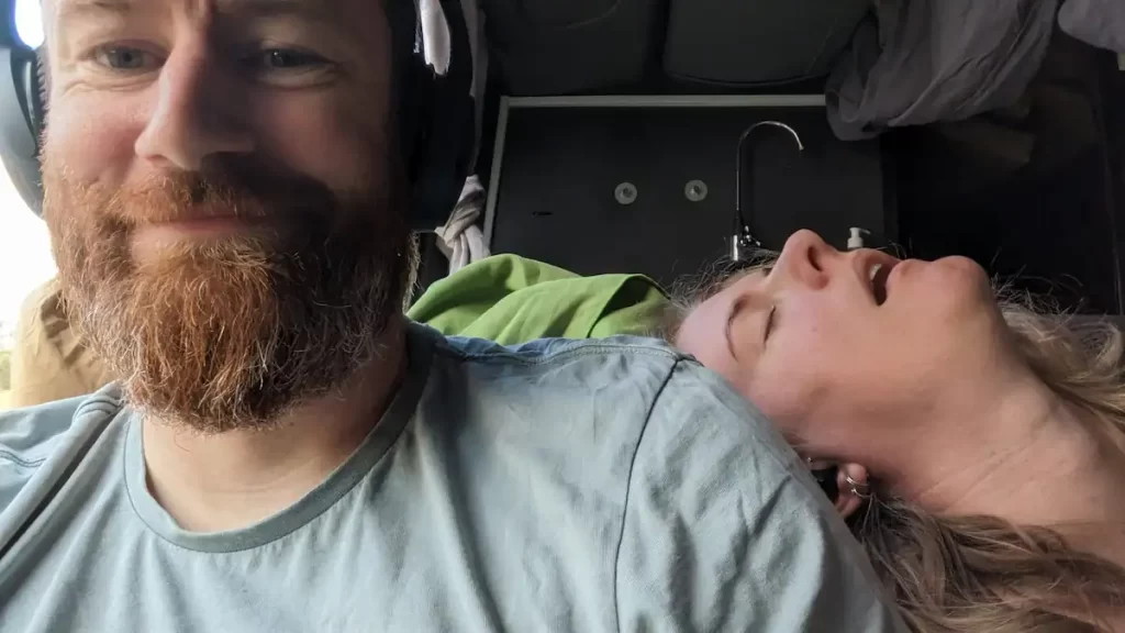 Young couple on a bus, the woman is sleeping with her mouth open while resting her head on the man's shoulder