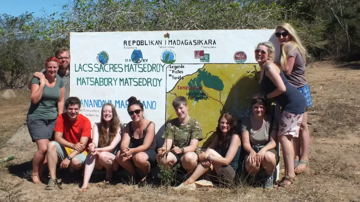 Group of young men and women in front of a painted sign for Matesdroy in Madagascar
