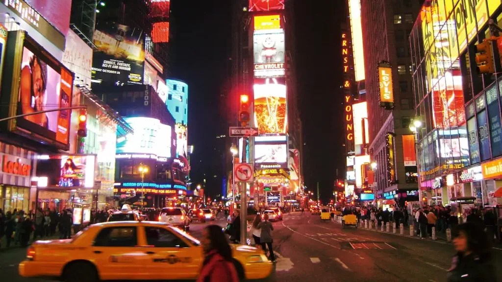 Neon lights of Times Square at night with lots of people and taxis around