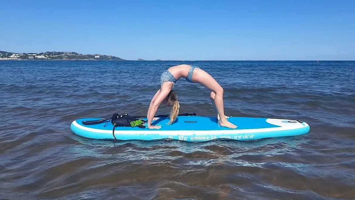 Woman doing a bridge pose on a paddleboard in the ocean