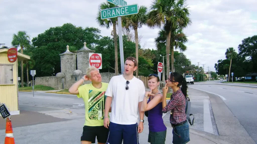 Two young men and two young women pulling 'confused' faces stood in front of a sign for Orange Street