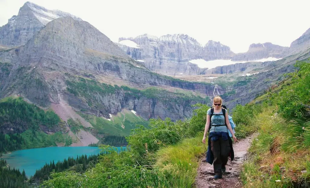 Young woman hiking with mountains in the background and a turquoise blue lake