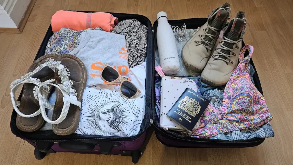 An unzipped suitcase filled with clothes, shoes and documents