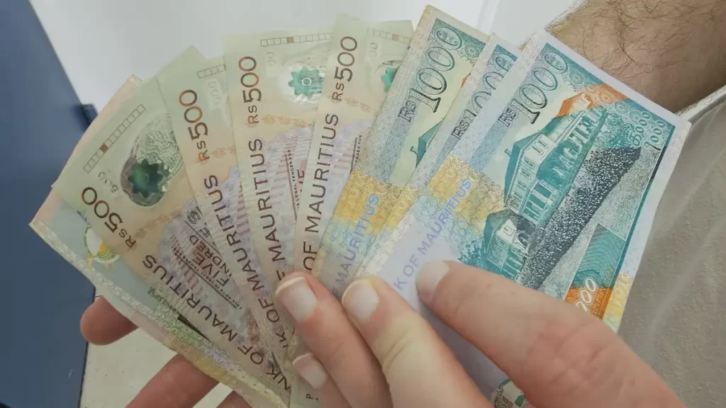 Close up of hands holding a variety of Mauritian rupee bank notes