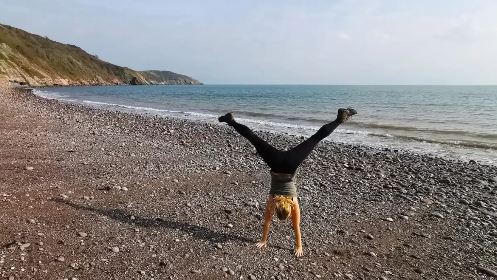 Woman doing a cartwheel on a rocky beach