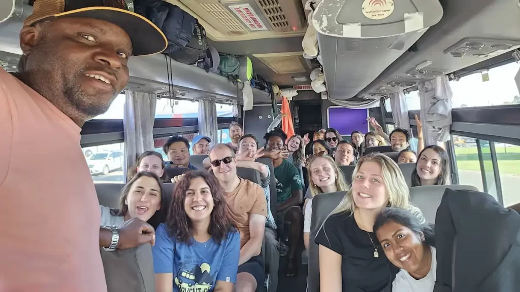 A middle age male tour guide taking a selfie of himself and his tour group inside a coach