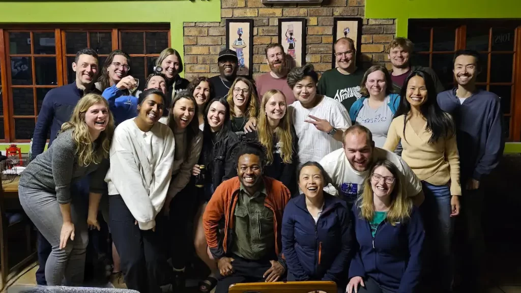 A group photo of approximately 20 young men and women all smiling and stood with their arms around each other