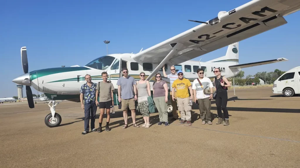 A group of young men and women stood outside a small propeller plane