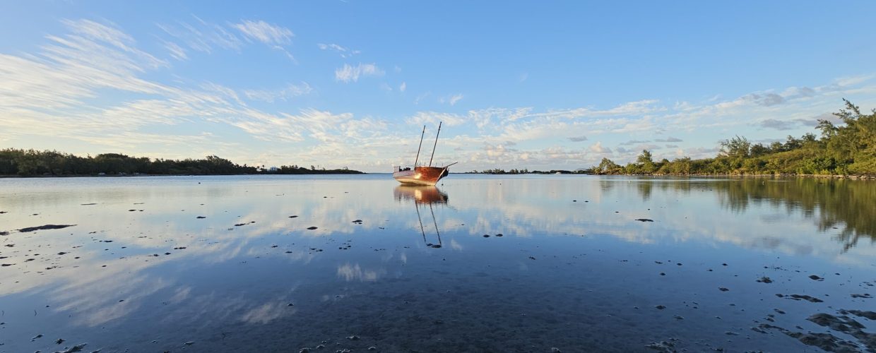 A boat reflecting on calm waters at Anse La Raie Beach Mauritius