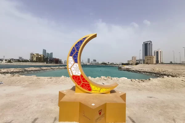 A moon and star statue in front of the Bahrain skyline