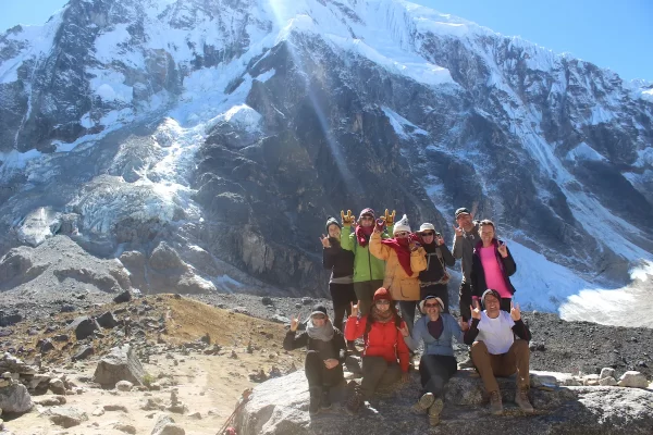 A group of young adults wearing winter clothing posing in front of a glacial mountain in Peru